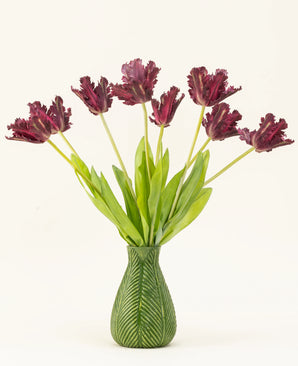 Sidens konstgjorda blombukett French Parakeet Tulip lila har mörklila, fransade tulpaner med långa gröna stjälkar i en vas med gröna bladmotiv, vilket skapar en slående visning mot en vit bakgrund.