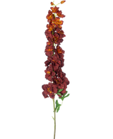 Den konstgjorda blomman Delphinium 105 cm bordeaux har en lång, enkel stjälk med flera mörkröda och orange konstgjorda blommor och gröna blad, isolerade på en vit bakgrund.