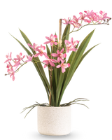 Artificiell växt Mini Cymbidium Real Touch 45 cm rosa har långa gröna blad och flera rosa blomstammar, arrangerade i en enkel kruka med vit struktur och mot en enkel bakgrund.