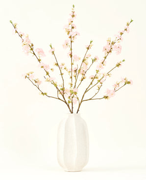 Sidens konstgjorda blombukett Körsbärsblommor ljusrosa 94 cm har känsliga rosa konstgjorda körsbärsblommor i en vit keramikvas, som tillför elegans mot en vanlig ljus bakgrund.