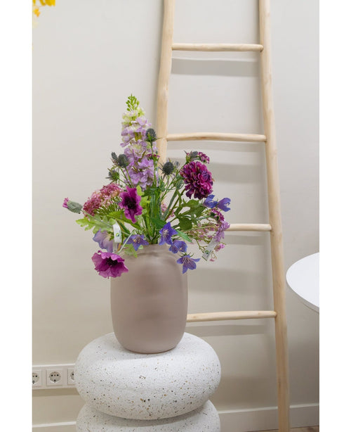 En konstgjord blommor Harebell av 62 cm lila står i en frostad glasvas på en strukturerad vit bas. Bakom den lutar en ljus trästege mot en beige vägg, med eluttag synliga nära golvet.
