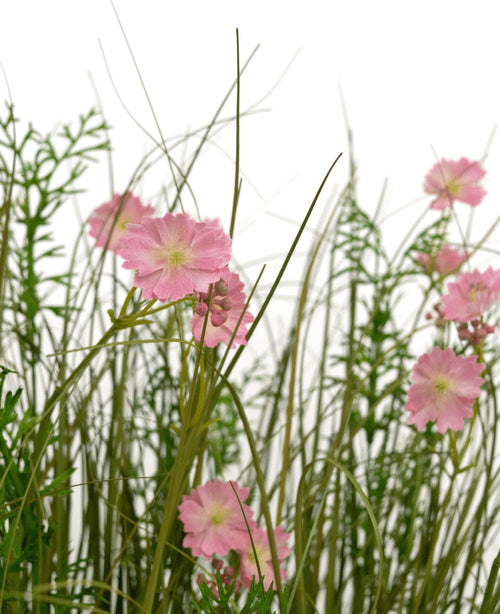 Konstgräs Rosa Gesang Flower Onion Grass Pot 90cm Fire Retardant har rosa blommor med ett ljusgrönt hjärta som blommar bland högt, tunt gräs och frodiga lövväxter, allt mot en vit bakgrund.