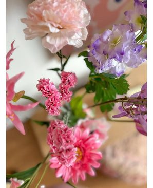 Een close-up van de Kunsttak Statice 64 cm roze, met delicate roze statice-bloemen en groene blaadjes, geschikt in een boeket tegen een zacht vervaagde achtergrond binnenshuis.