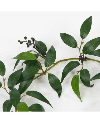 En Artificiell Smilax-girland på 180 cm med långa, smala gröna blad och små klasar av mörka, runda bär, avbildade mot en vit bakgrund.