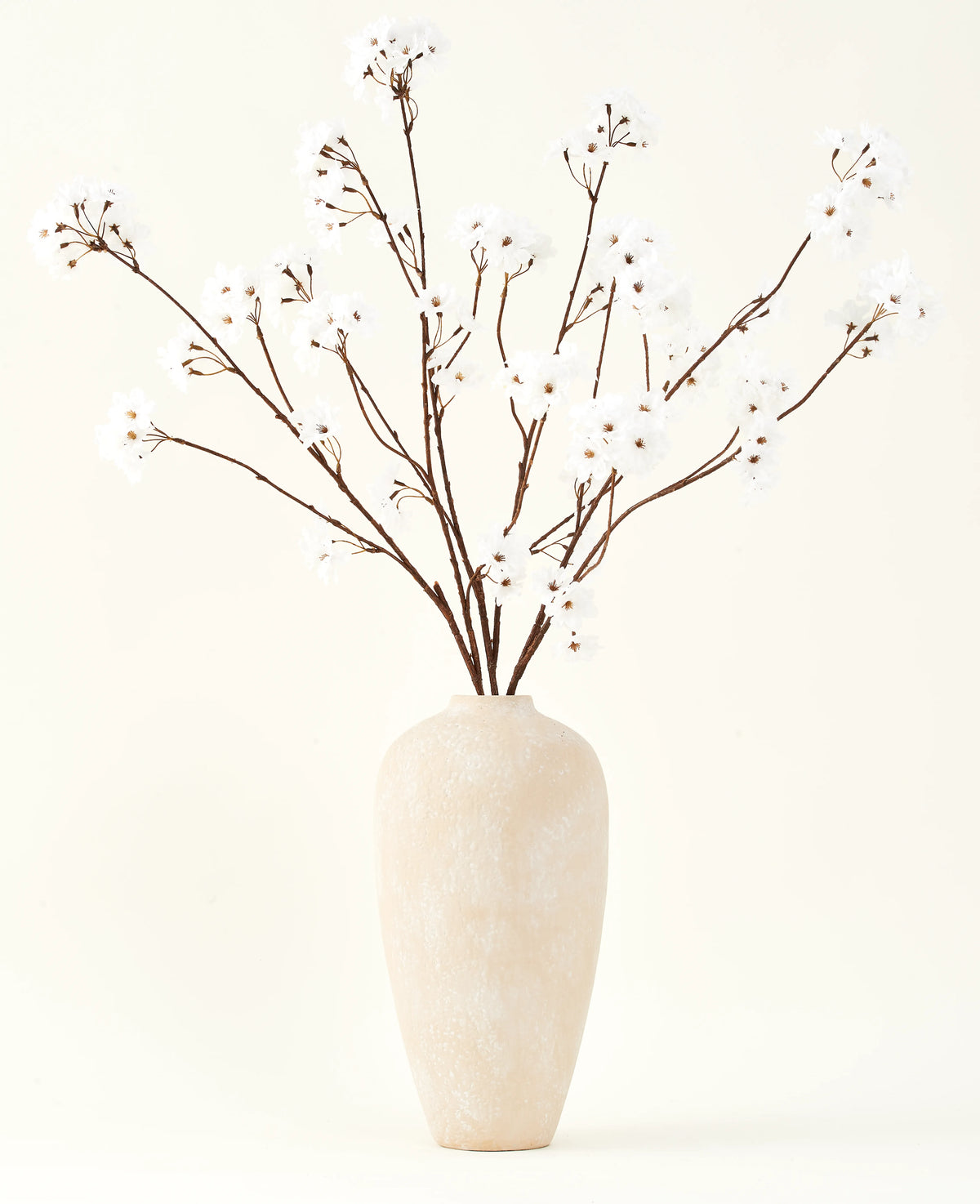 Silk konstgjorda blombuketten Cherry blossom cream 114 cm står högt i en beige keramikvas och ger en fridfull dekoration till alla rum med sina delikata, krämfärgade grenar mot en ljus bakgrund.