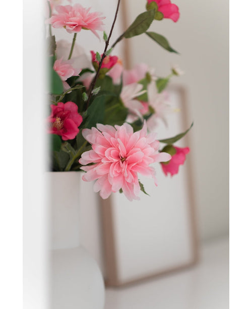 En närbild på Konstgjorda Blomman Dahlia 68 cm rosa i en vit vas, med en svag fotoram i bakgrunden på en vit yta.
