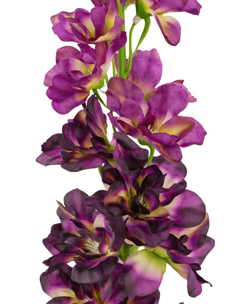 En närbild av den konstgjorda blomman Delphinium Purple 79 cm, en hög konstgjord stjälk med flera lila och mörklila blommor med ett grönt och gult hjärta, mot en vit bakgrund.