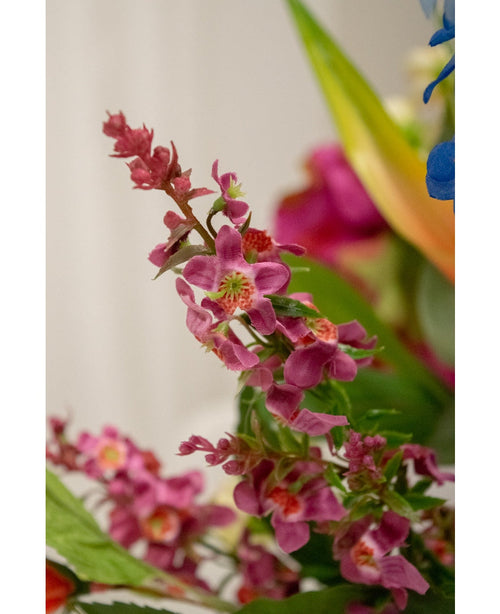 Närbild av artificiell blomma kattmynta 75 cm rosa: ett kluster av ljust rosa konstgjorda blommor med ett grönt hjärta och frodiga blad, skarpt avbildad mot en mjukt suddig bakgrund med inslag av andra blommor.