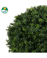 Close-up van Kunstplant Buxus op stam romeinse stijl UV 85cm, een ronde kunst buxusstruik met dichte, kleine groene bladeren. In de linkerbovenhoek staat een UV-beschermingssymbool met een zonne-icoon.
