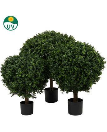 De Kunstplant Buxus op stam romeinse stijl UV 85cm heeft drie kunstmatige buxusbomen in zwarte potten met dicht, rond groen gebladerte, tegen een witte achtergrond met een UV-beschermingssymbool in de linkerbovenhoek.