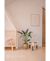 Een minimale kinderkamer met een licht houten wiegje, Kunstplant Heliconia 110 cm, houten speelgoed en eenvoudige muurkunst in een lichte, opgeruimde kamer - perfecte inspiratie voor kleine ruimtes inrichting.