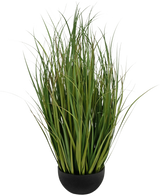 De Kunstgras Dogtail uiengras Bran, een 90 cm brandvertragende kunstplant met lange, slanke groene bladeren, wordt geleverd in een zwarte ronde pot en is afgebeeld tegen een effen witte achtergrond.
